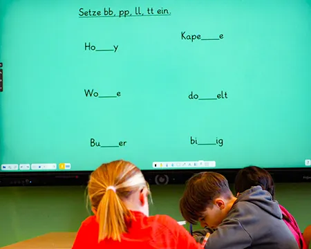 Kinder lernen vor der elektronischen Tafel im Klassenraum