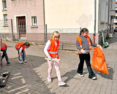 Kinder mit Warnwesten und Greifzangen auf dem Schulhof