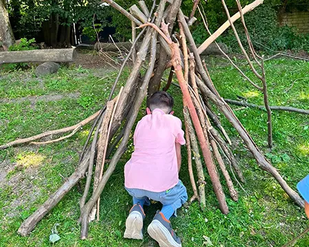 Lehrkraft und Kinder beim Bau des Tipis