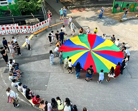 Kinder schwingen auf dem Schulhof das Schwungtuch